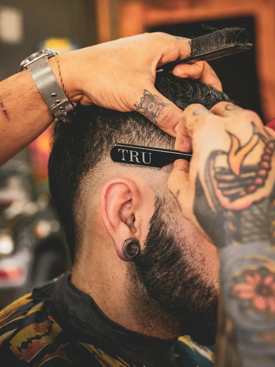 Barbeiro a aparar o cabelo e a barba de um cliente